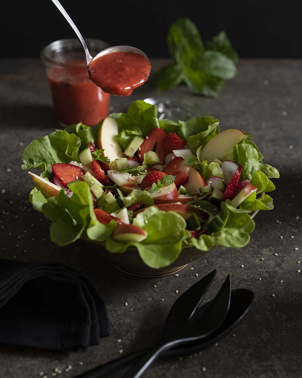 Mit einer Schöpfkelle geben wir das Erdbeer-Dressing auf den Salat.