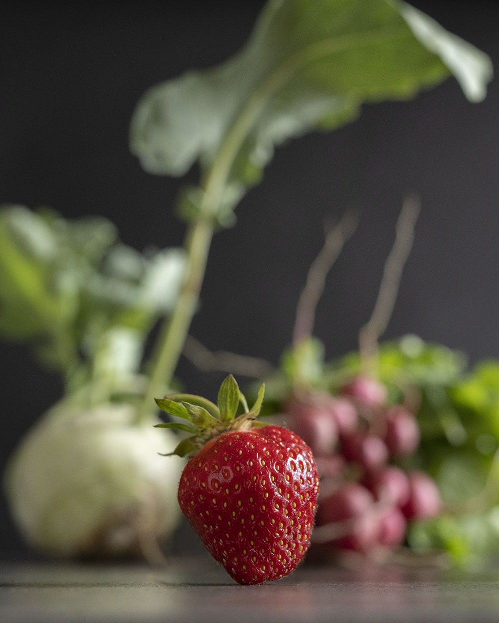 Alle Zutaten unseres Salats und für unser Erdbeerdressing auf einen Blick. Im Vordergrund steht eine frische Erdbeere.