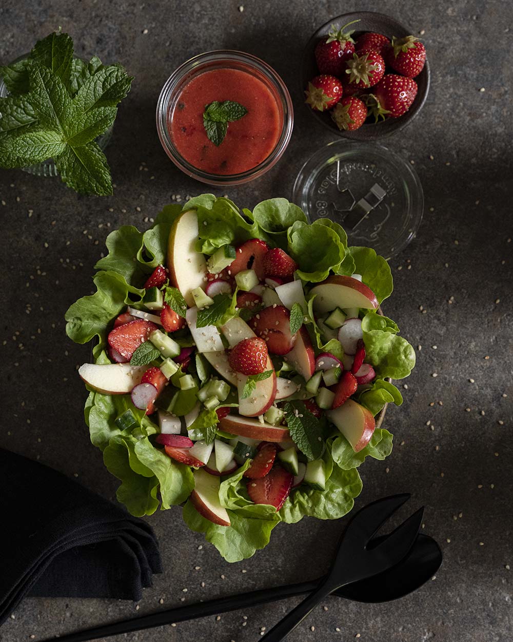 Unser fertig angerichteter Salat steht auf dem Tisch. Wir haben ihn von oben fotografiert und daneben frische Erdbeeren und ein Glas mit unserem selbstgemachten Erdbeerdressing gestellt.