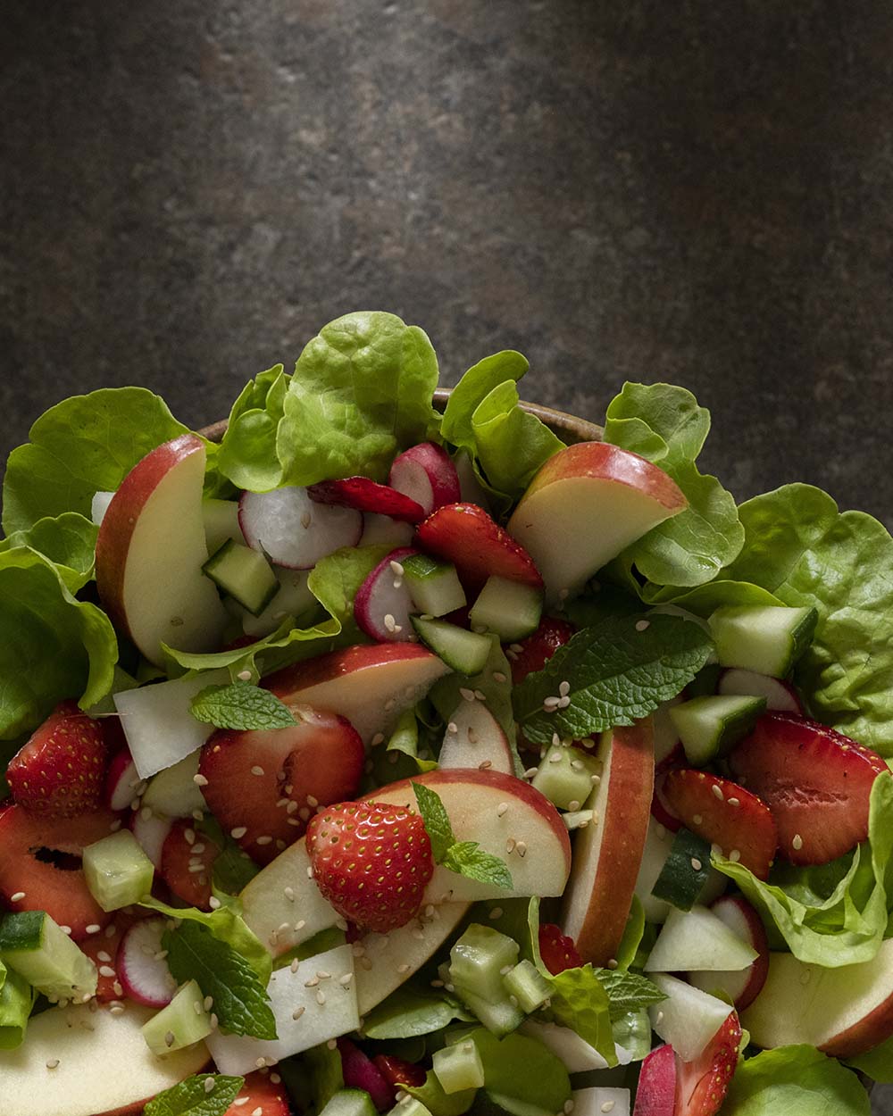Ein bunter Sommer-Salat mit frischen Salatblättern, Kohlrabi, Erdbeeren, Radieschen, Gurke und Apfel.